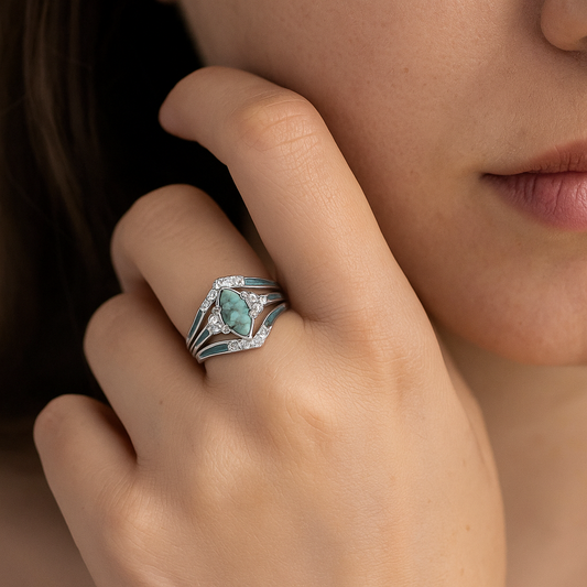 Close-up of a hand wearing a decorative ring with a turquoise stone.