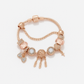 Rose gold bracelet with various charms on a light background