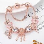 Rose gold bracelet with various charms on a magazine page background