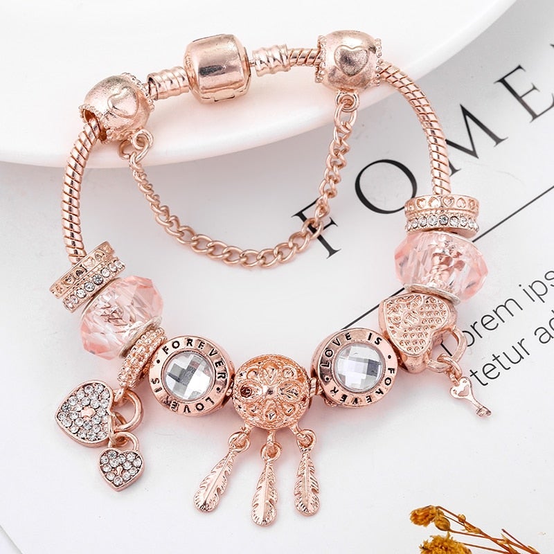 Rose gold bracelet with various charms on a magazine page background