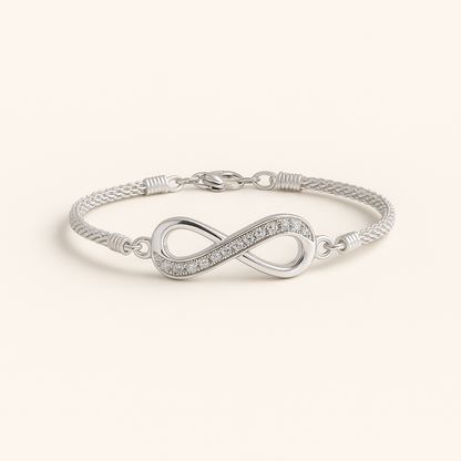 Silver infinity bracelet on a light beige background