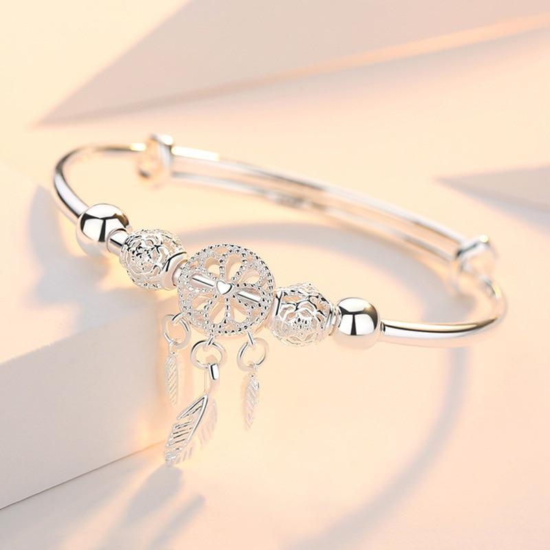 Silver dreamcatcher bracelet with intricate bead and feather charms, elegant jewelry accessory, perfect for boho fashion and gift ideas.