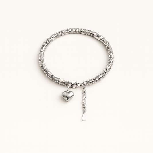 Silver bracelet with a heart charm on a white background
