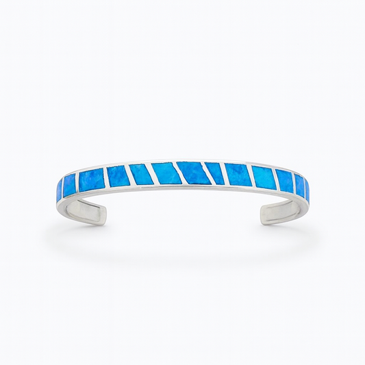 Silver cuff bracelet with vibrant blue opal inlay, geometric design. Elegant jewelry accessory, perfect for fashion-forward style.
