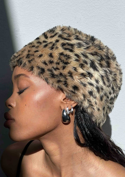 Person wearing a leopard print headband against a light background
