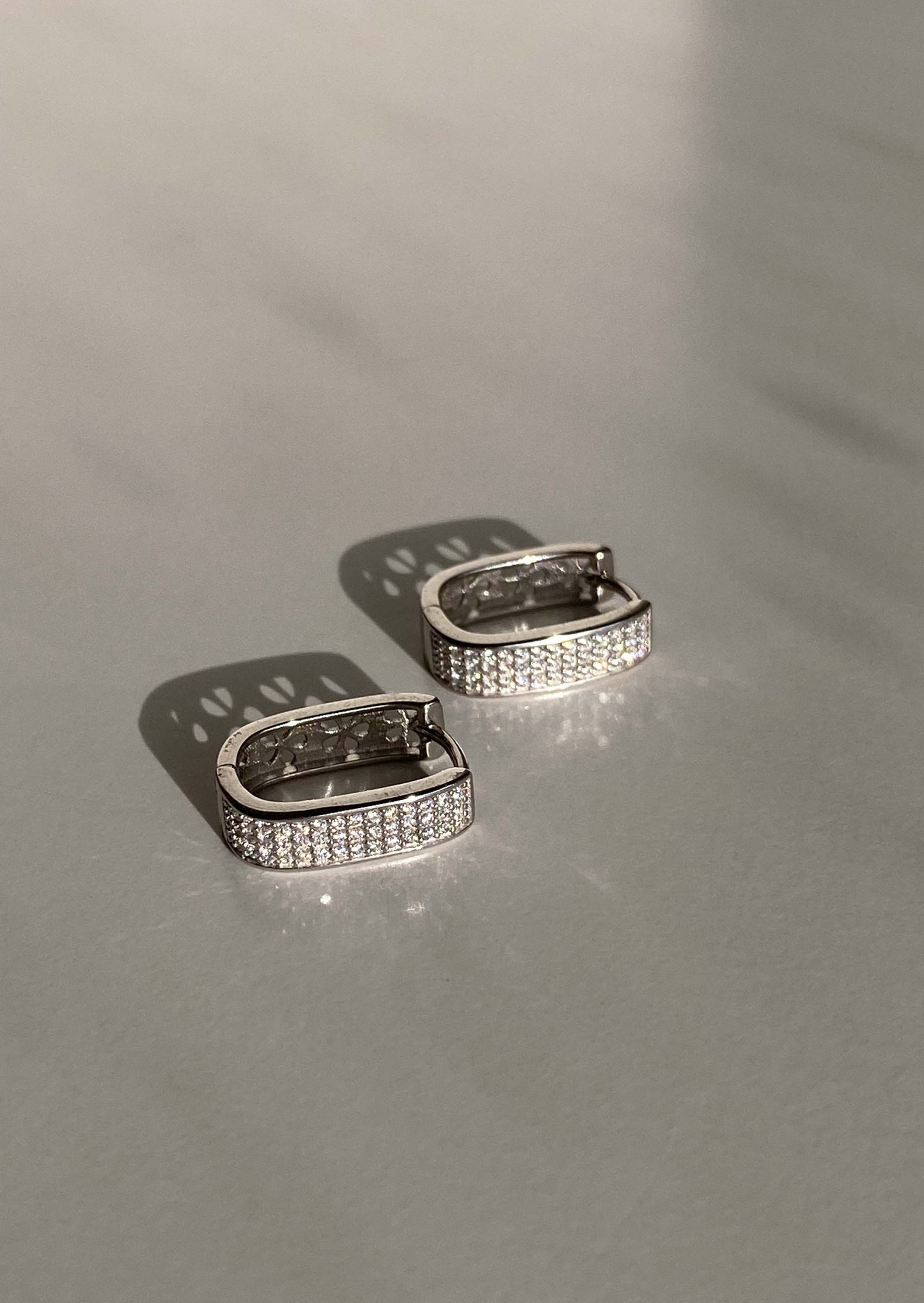 Pair of silver hoop earrings on a light gray surface