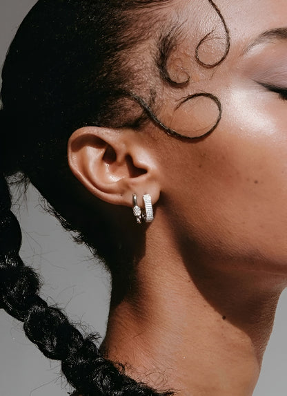 Close-up of a person's ear with a hoop earring against a neutral background