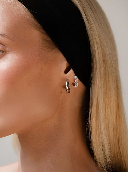 Close-up of a person wearing gold hoop earrings with a neutral background
