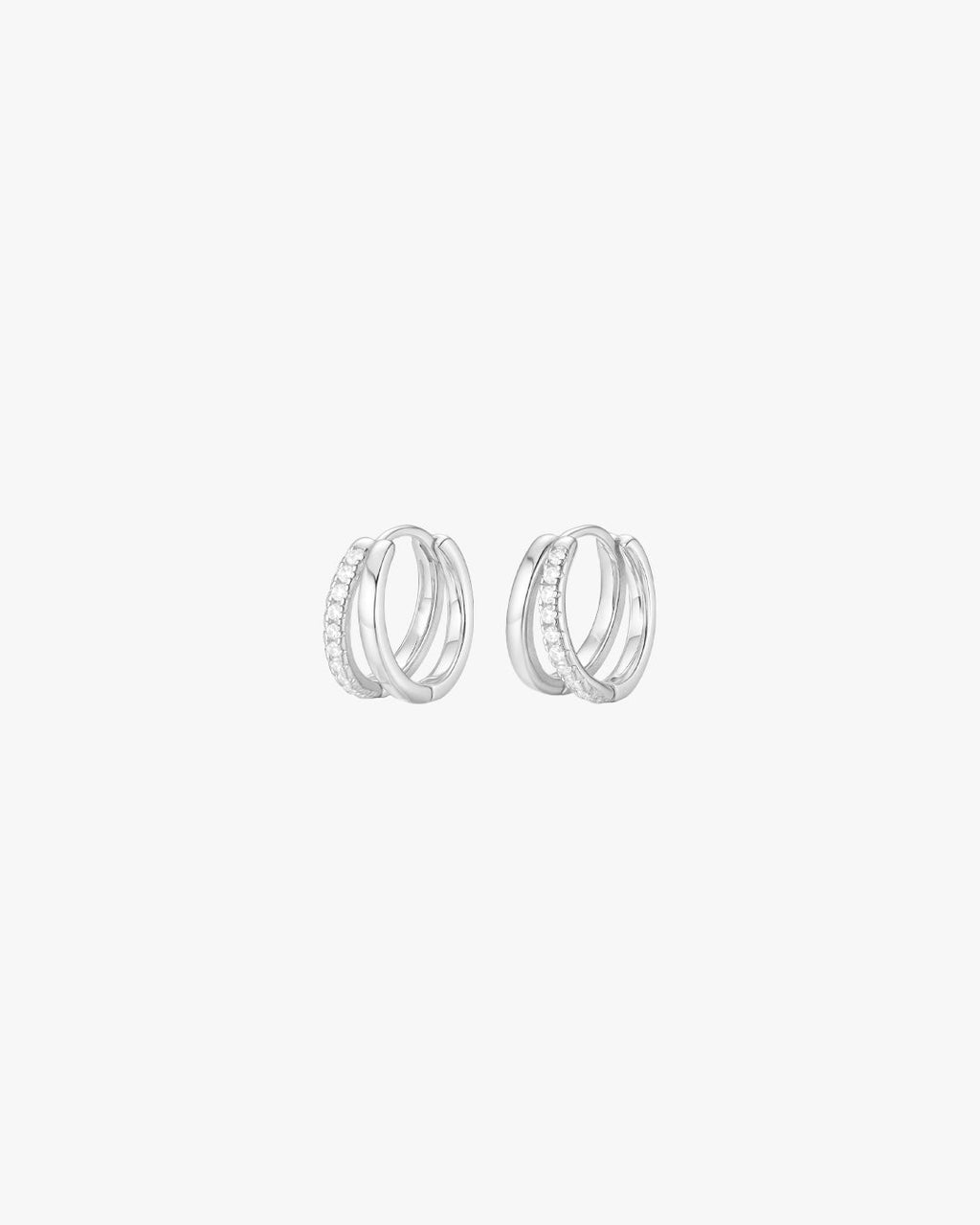 Silver hoop earrings with embedded crystals, minimalist design, isolated on white background. Elegant jewelry, fashion accessory, women's earrings.