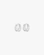 Silver hoop earrings with embedded crystals, minimalist design, isolated on white background. Elegant jewelry, fashion accessory, women's earrings.