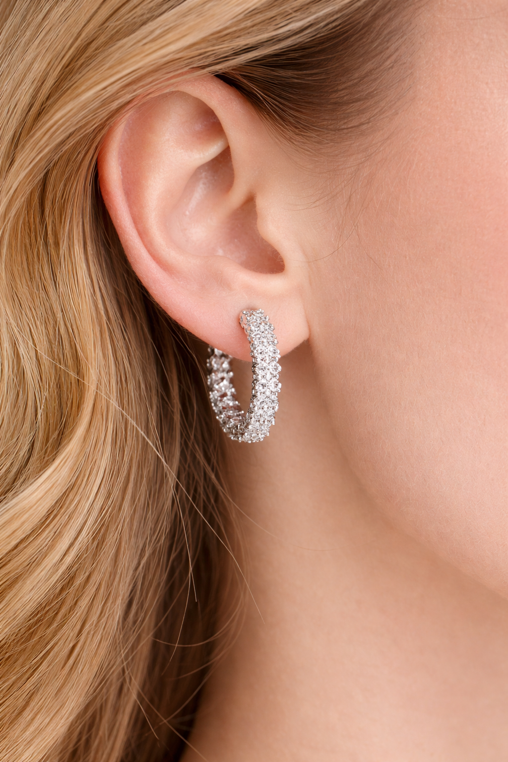 Close-up of a person wearing a silver hoop earring with a blurred background