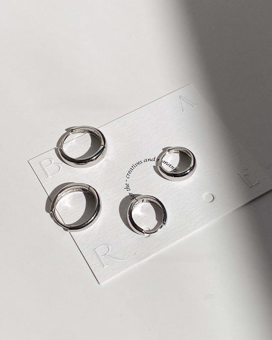 Set of silver hoop earrings on a branded card with 'BORA' branding.