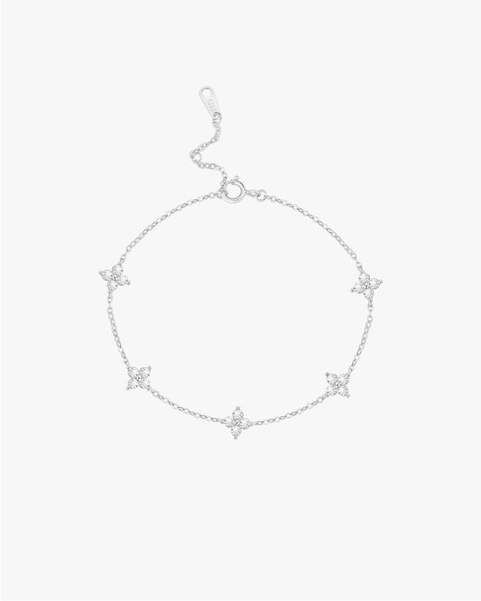 Silver bracelet with star-shaped charms on a light gray background