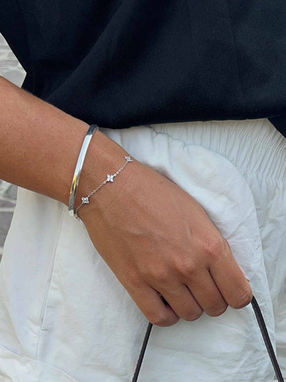 Hand wearing a silver bracelet with star design on a blurred background