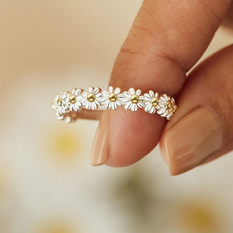 Gold and silver floral ring on a finger with a blurred background