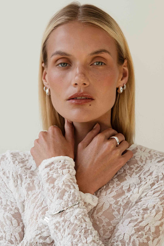 Woman wearing a white lace top with a plain background