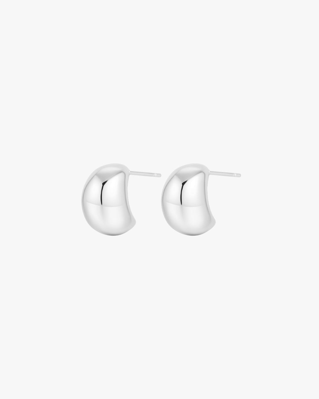 Silver crescent-shaped stud earrings on white background, minimalist jewelry, modern fashion accessory, polished finish, elegant design.
