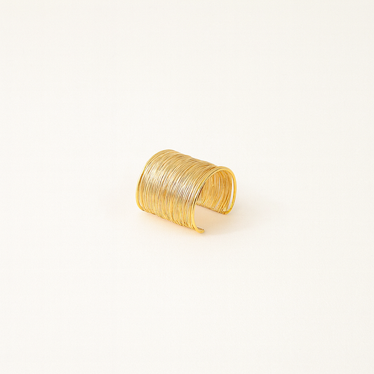 Gold cuff bracelet with textured, layered design on a plain white background. Elegant jewelry accessory, perfect for fashion and style enthusiasts.