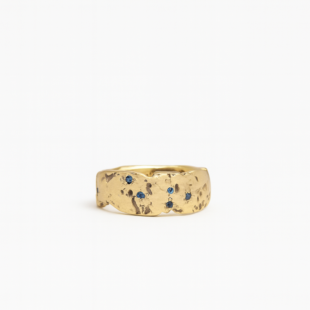 Gold ring with blue gemstones on a white background