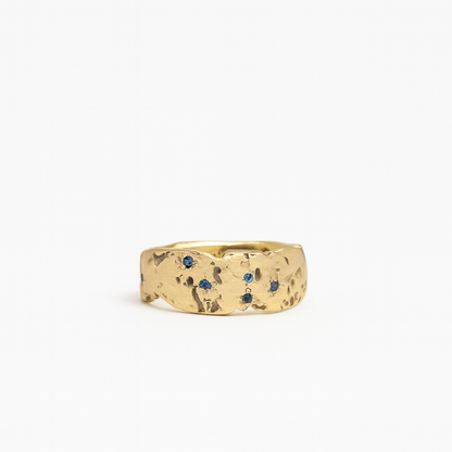 Gold ring with blue gemstones on a white background