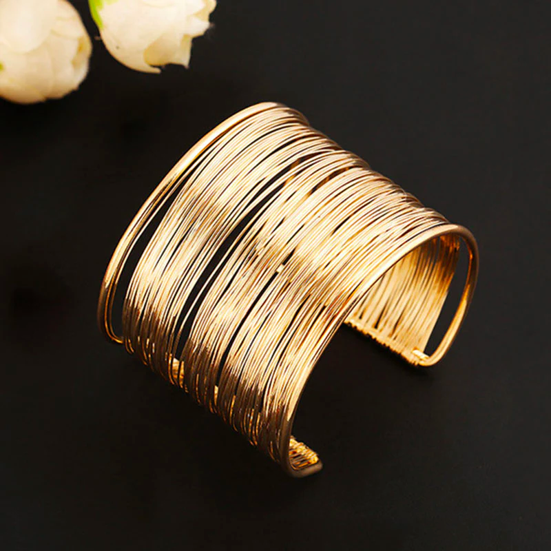 Gold wire cuff bracelet on black background, elegant jewelry accessory, modern fashion statement piece, women's wristwear, chic design.