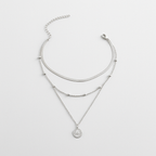 Triple-layered silver necklace with a coin pendant, featuring a sleek chain, beaded accents, and adjustable clasp. Elegant jewelry for women.
