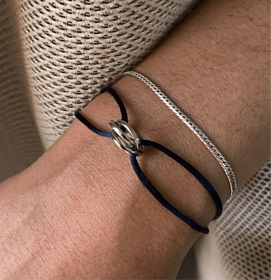 Close-up of a wrist wearing two bracelets with a textured fabric background