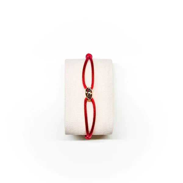 Red bracelet on a white cylindrical object with a white background