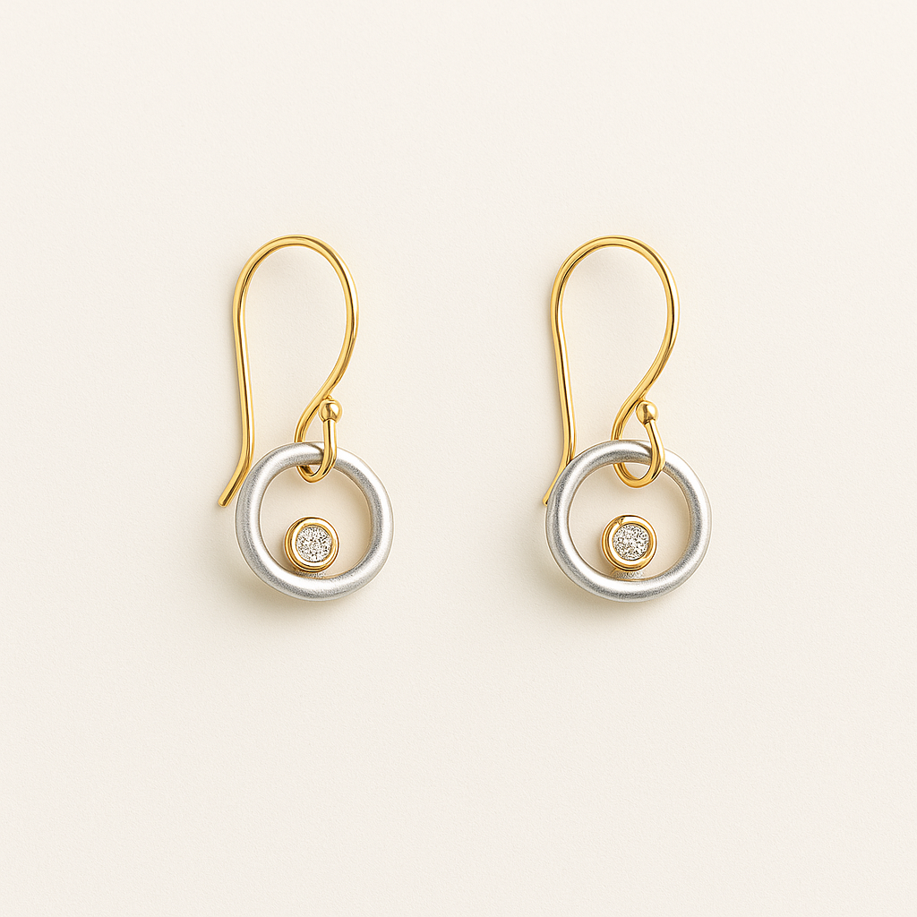 Pair of gold and silver earrings with gemstones on a beige background