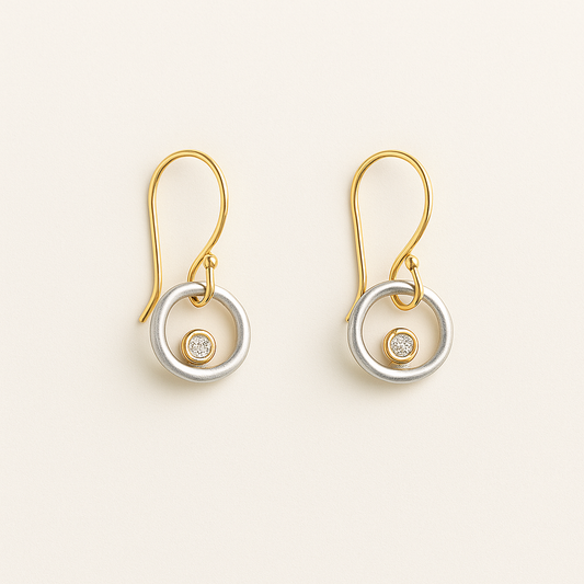 Pair of gold and silver earrings with gemstones on a beige background