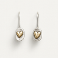 Pair of silver earrings with gold heart designs on a light gray background