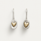 Pair of silver earrings with gold heart designs on a light gray background