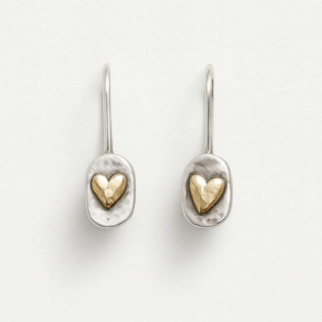 Pair of silver earrings with gold heart designs on a light gray background