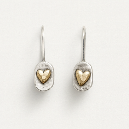 Pair of silver earrings with gold heart designs on a light gray background