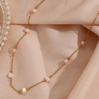 Elegant gold chain necklace with pearls on a soft beige fabric background, showcasing luxury jewelry design and fashion accessory trends.