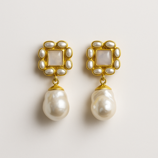 Pair of pearl earrings with gold frames on a light gray background