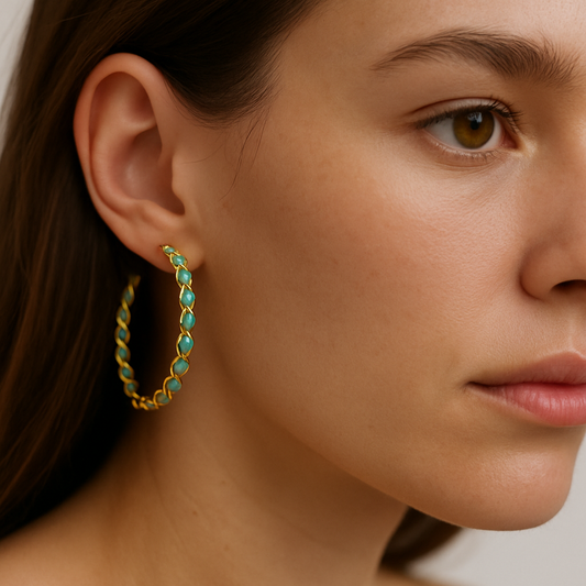 Close-up of a woman wearing gold hoop earrings with turquoise stones.