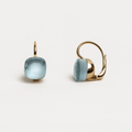 Gold earrings with light blue gemstones on a white background