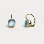 Gold earrings with light blue gemstones on a white background