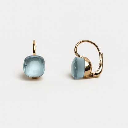 Gold earrings with light blue gemstones on a white background