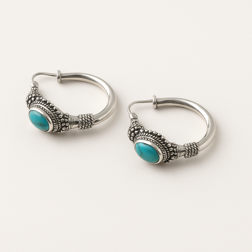 Pair of silver hoop earrings with turquoise stones on a white background