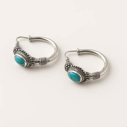 Pair of silver hoop earrings with turquoise stones on a white background