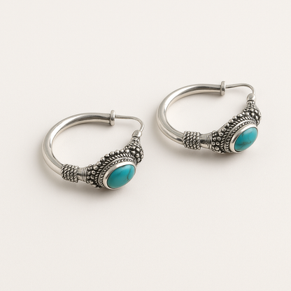 Silver hoop earrings with turquoise stones on a white background