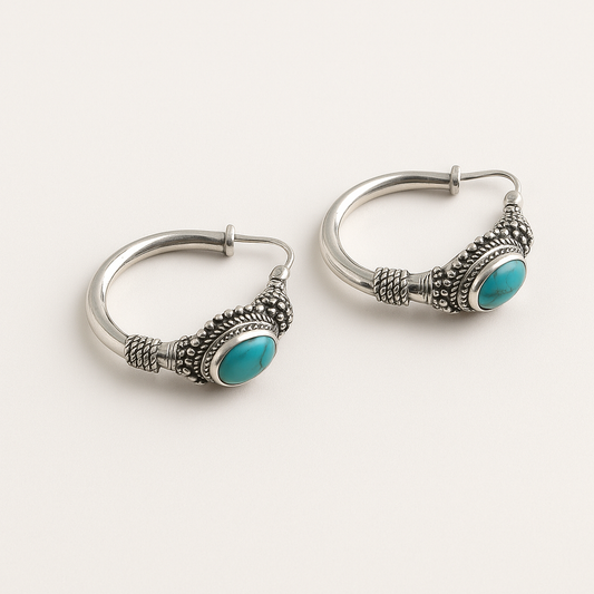 Silver hoop earrings with turquoise stones on a white background
