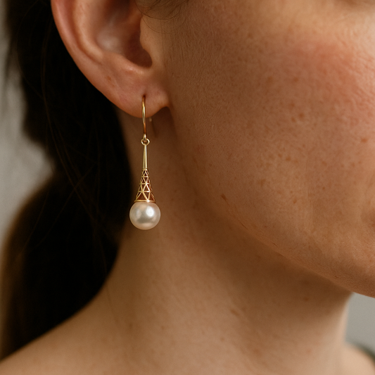 Close-up of a pearl earring on an ear against a neutral background