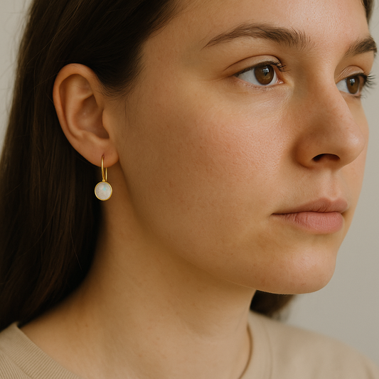 Close-up of a woman wearing a gold earring with a pearl drop.