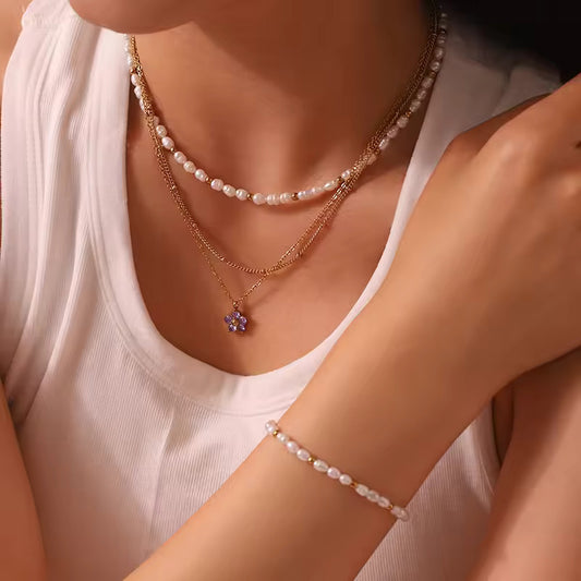 Close-up of a person wearing multiple pearl necklaces and an anklet on a neutral background