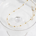 Pearl and gold beaded necklace on a clear glass dish