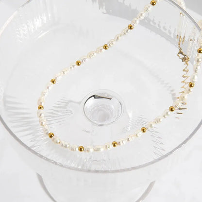 Pearl and gold beaded necklace on a clear glass dish
