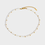 Necklace with white pearls and gold beads on a light gray background